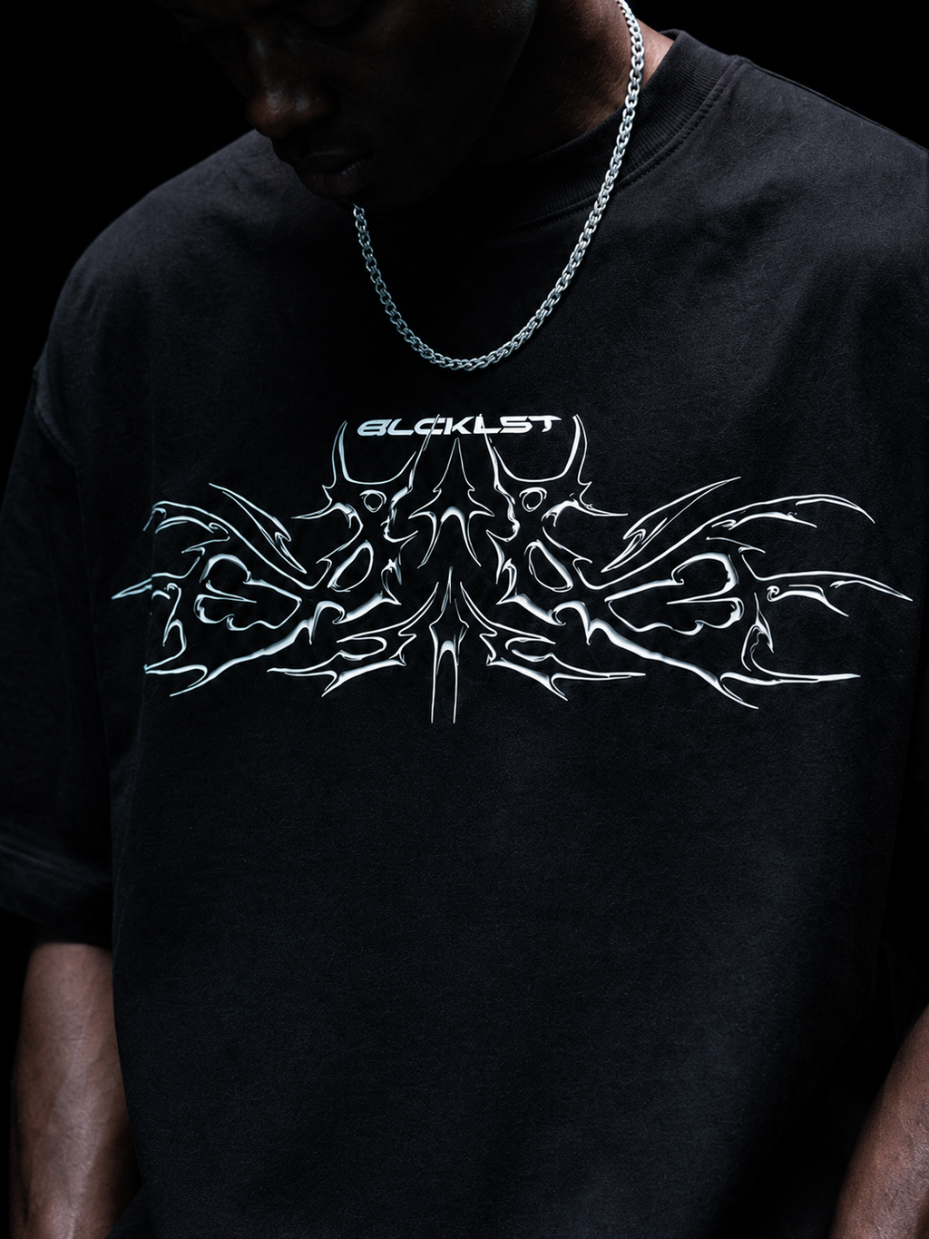 Black 220 GSM oversized t-shirt with white chrome tribal graphic front print, close-up detail