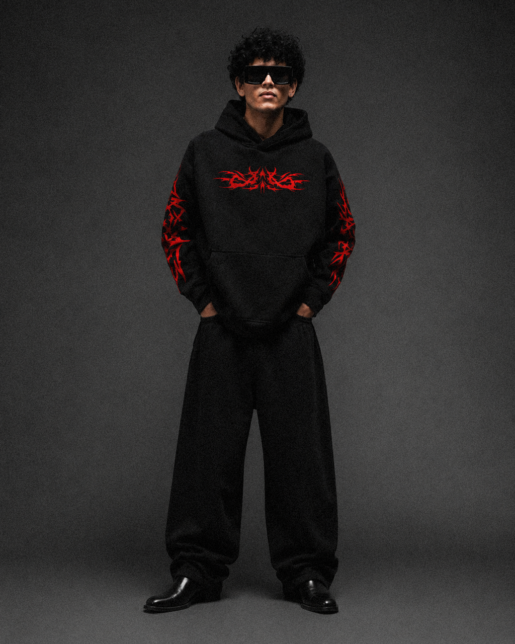 Black 350 GSM oversized hoodie with red tribal graphic prints on the chest and sleeves, full-body model